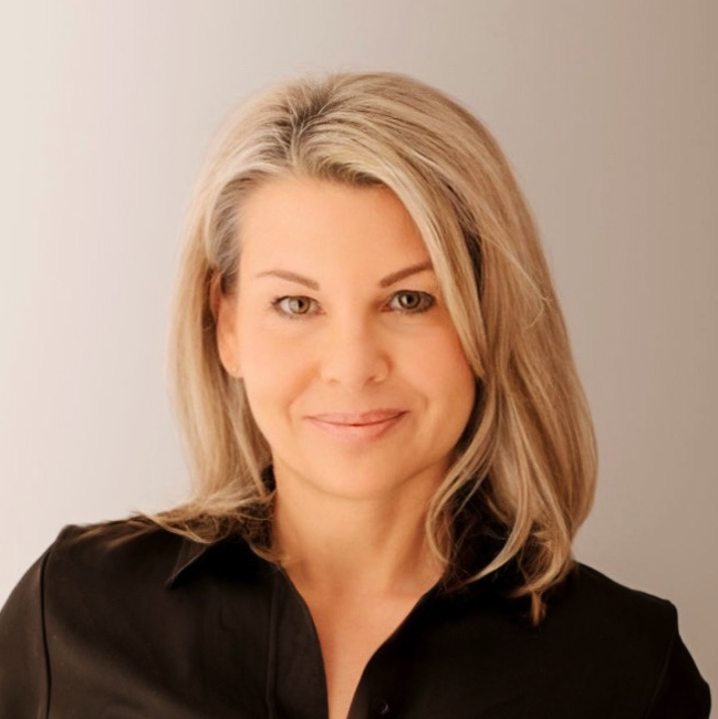 Portrait einer blonden Frau, schwarzes Oberteil, sie blickt melancholisch-zuversichtlich in die Kamera